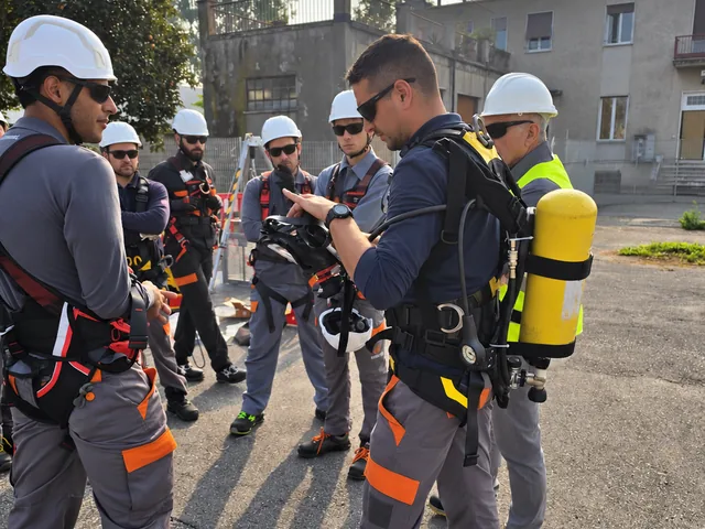 Un formatore mostra un dispositivo respiratorio ai partecipanti disposti in cerchio all’aperto.